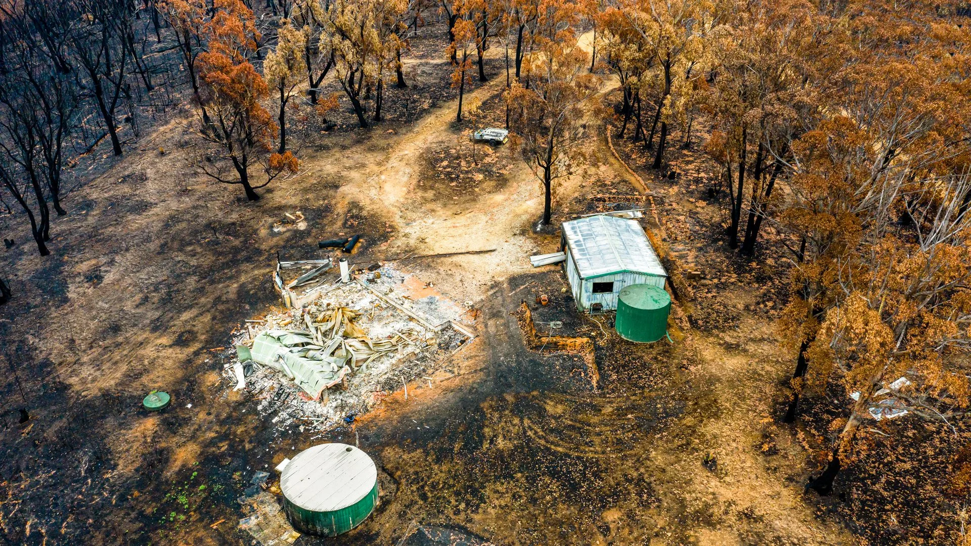 Aerial view of a fire-damaged rural property surrounded by burnt trees